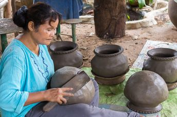 woman making a clay pot using a paddle