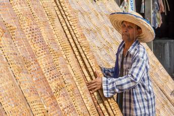 man holding rack full of spring roll wrappers