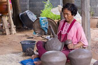 woman making a clay pot using a paddle