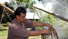 man starting fire at end of bamboo tube