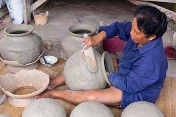 woman making pottery with a paddle