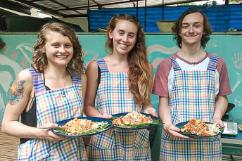 three students holding plates of pat thai