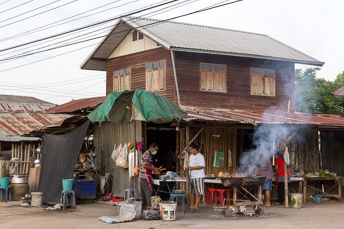 people grilling meat in front of a wooden house