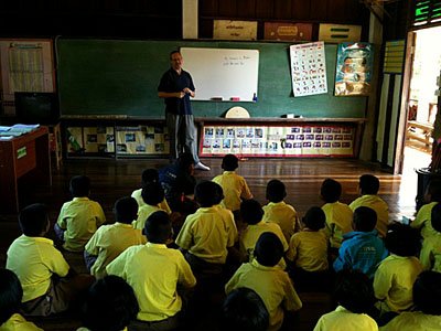 man teaching English to young students