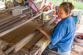 woman weaving a sitting mat