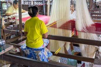 four women working on a giat loom